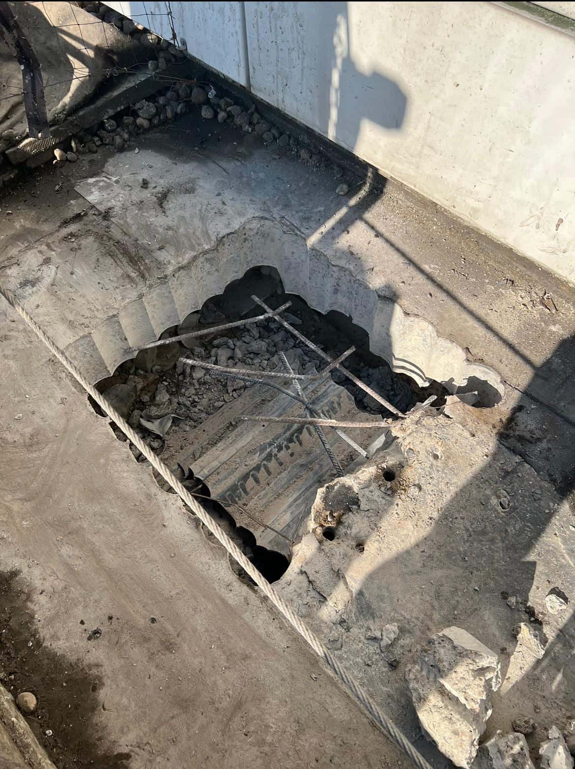 Stitch-drilled opening in a concrete roof slab with exposed reinforcement bars, seen from above