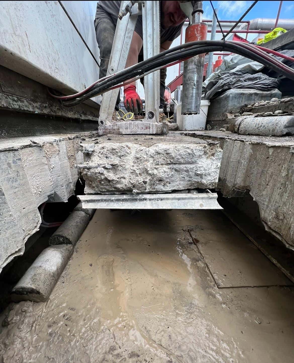 Cut concrete block raised clear of a slab opening on a lifting frame, with the scalloped core edges visible below