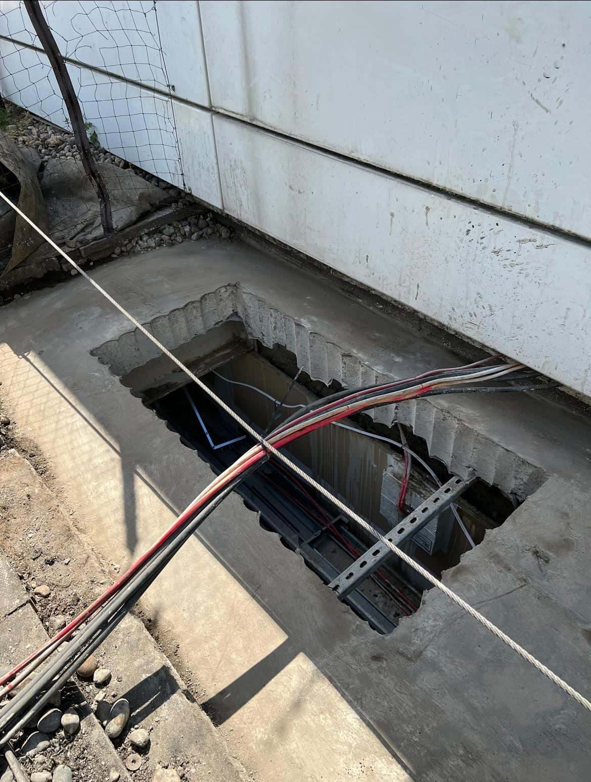 Rectangular stitch-drilled opening in a roof walkway with cable tray and services visible in the space below