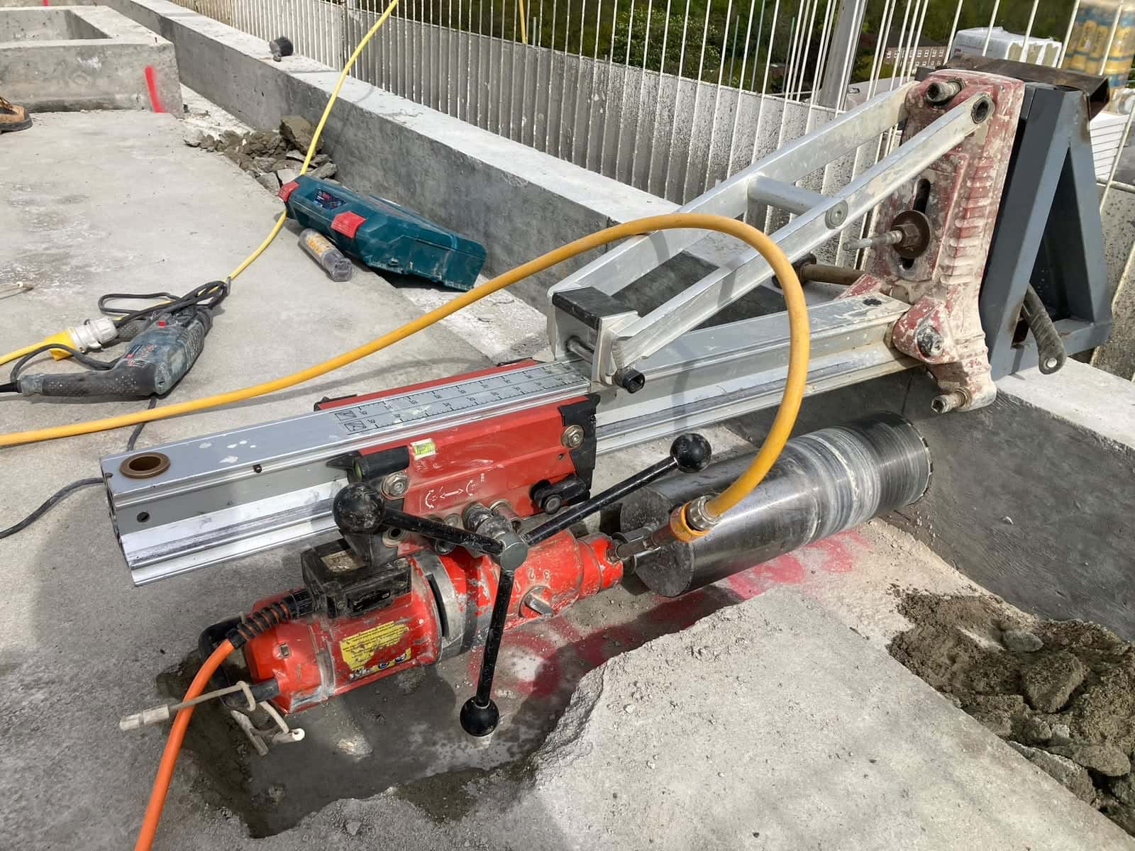 Core drill rig set up on a concrete roof deck, drilling horizontally into a concrete upstand